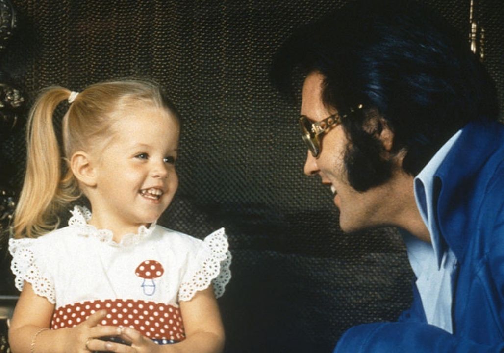 “In February 1968, the world paused as Elvis Presley stepped out of the hospital carrying his newborn daughter, Lisa Marie. For a fleeting moment, the King of Rock and Roll vanished—leaving only a father, tender and protective, cradling new life in his arms. Staff and visitors later recalled an almost sacred stillness. Phones stopped ringing, conversations hushed, and even the bustling hospital seemed to slow. Elvis hummed softly, rocked his daughter gently, and moved with a care that no stage performance could capture. Fame lingered, but it was the quiet gravity of fatherhood that held everyone’s attention. Those who witnessed it never forgot the sight—not for the celebrity, but for the humanity. In that hallway, in that embrace, a new chapter had begun: one written not in songs, but in love…”